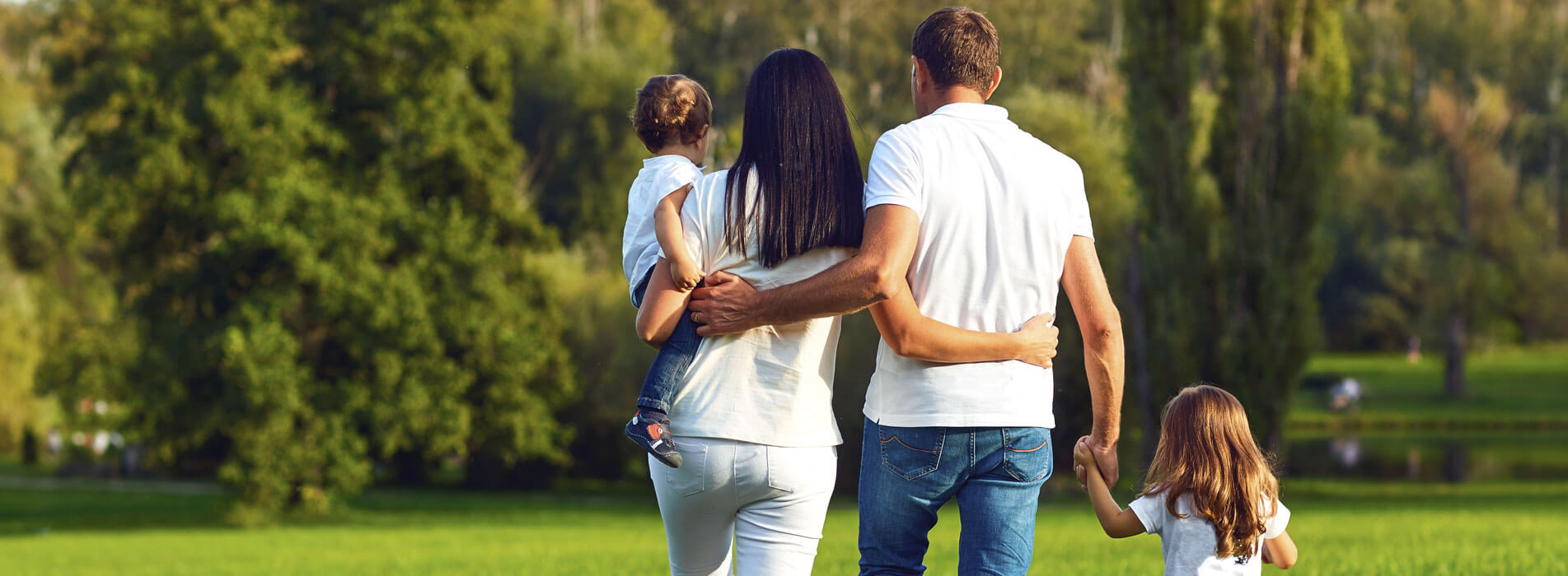 Rear View. Happy Family With Children Walking In The Park.
